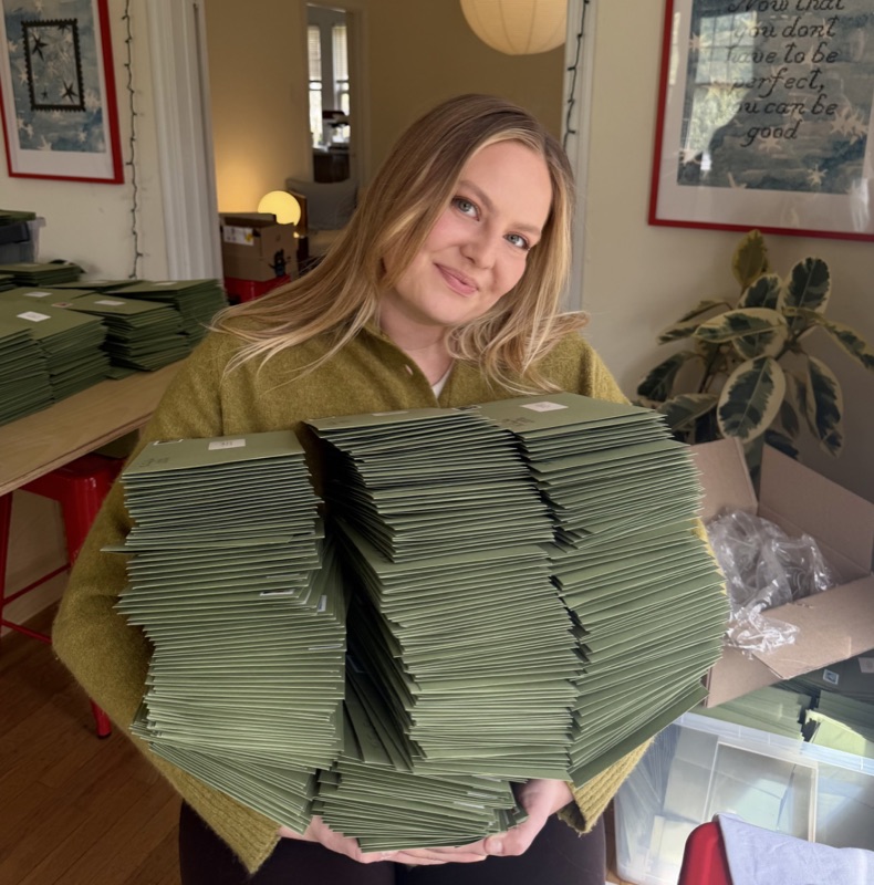 Hannah Gustafson holding stacks of Tiny Post envelopes